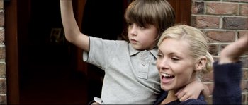 Movie still from “Kill List” (2011), directed by Ben Wheatley – A woman and a boy are smiling for the camera; Close Up shot, High angle
