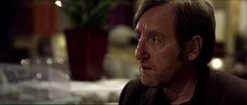 Movie still from “Kill List” (2011), directed by Ben Wheatley – A person wearing a suit; Close Up shot, Over the shoulder angle