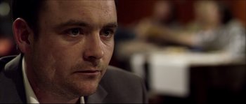 Movie still from “Kill List” (2011), directed by Ben Wheatley – A person wearing a suit; Close Up shot, Over the shoulder angle