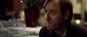 Movie still from “Kill List” (2011), directed by Ben Wheatley – A person wearing a suit and tie; Close Up shot, Over the shoulder angle