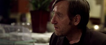 Movie still from “Kill List” (2011), directed by Ben Wheatley – A person wearing a suit and tie; Close Up shot, Over the shoulder angle