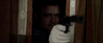 Movie still from “Kill List” (2011), directed by Ben Wheatley – A man holding a gun in front of a mirror; Close Up shot, Low angle