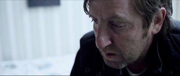 Movie still from “Kill List” (2011), directed by Ben Wheatley – A person looking down at something; Close Up shot, Over the shoulder angle