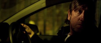 Movie still from “Kill List” (2011), directed by Ben Wheatley – A man sitting in the driver's seat of a car; Close Up shot, Over the shoulder angle