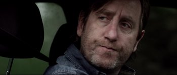 Movie still from “Kill List” (2011), directed by Ben Wheatley – A person wearing a jean jacket; Close Up shot, Over the shoulder angle