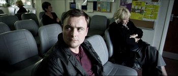 Movie still from “Kill List” (2011), directed by Ben Wheatley – A man and a woman sitting in a car; Medium shot, Over the shoulder angle