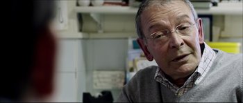 Movie still from “Kill List” (2011), directed by Ben Wheatley – An older man wearing glasses looking at the camera; Close Up shot, Over the shoulder angle