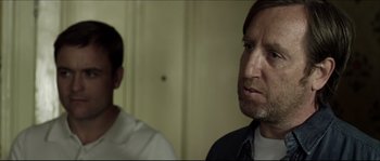 Movie still from “Kill List” (2011), directed by Ben Wheatley – A man with a beard and a man with short hair; Close Up shot, Over the shoulder angle