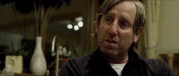 Movie still from “Kill List” (2011), directed by Ben Wheatley – A person wearing a black shirt; Close Up shot, Over the shoulder angle