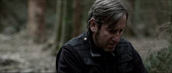 Movie still from “Kill List” (2011), directed by Ben Wheatley – A person wearing a black jacket; Close Up shot, Over the shoulder angle