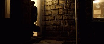 Movie still from “Kill List” (2011), directed by Ben Wheatley – A man is standing in the doorway of a house; Wide shot, Low angle