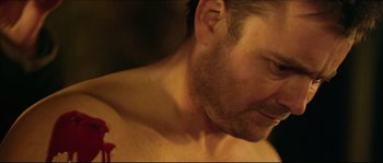 Movie still from “Kill List” (2011), directed by Ben Wheatley – A man's face and chest; Close Up shot, Over the shoulder angle