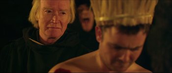 Movie still from “Kill List” (2011), directed by Ben Wheatley – A group of people sitting in a dark room; Close Up shot, Over the shoulder angle