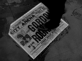 Movie still from “Killer's Kiss” (1955), directed by Stanley Kubrick – A person is walking on the sidewalk in the rain; Wide shot, High angle