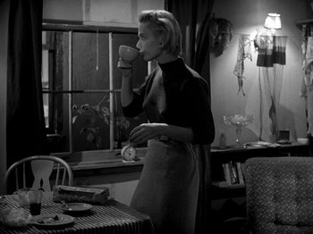 Movie still from “Killer's Kiss” (1955), directed by Stanley Kubrick – A black and white photo of a woman drinking a cup of coffee; Medium shot, Over the shoulder angle