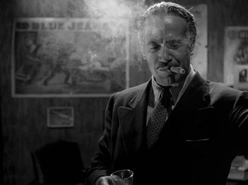 Movie still from “Killer's Kiss” (1955), directed by Stanley Kubrick – An older man in a suit smoking a cigarette; Medium shot, Low angle