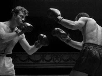 Movie still from “Killer's Kiss” (1955), directed by Stanley Kubrick – Two men boxing in a boxing ring in black and white; Medium shot, Low angle
