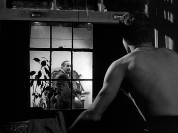 Movie still from “Killer's Kiss” (1955), directed by Stanley Kubrick – A black and white photo of a man looking in a mirror; Medium shot, Over the shoulder angle