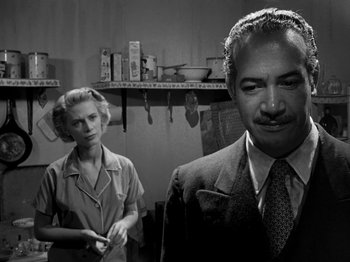 Movie still from “Killer's Kiss” (1955), directed by Stanley Kubrick – An older man and a younger woman standing in a kitchen; Medium shot, Low angle