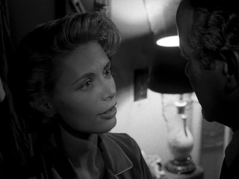 Movie still from “Killer's Kiss” (1955), directed by Stanley Kubrick – A woman sitting next to a man in front of a lamp; Close Up shot, Over the shoulder angle