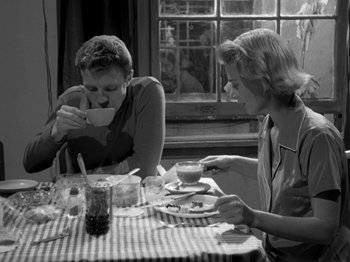 Movie still from “Killer's Kiss” (1955), directed by Stanley Kubrick – Two people sitting at a table eating food and drinking coffee; Medium shot, High angle