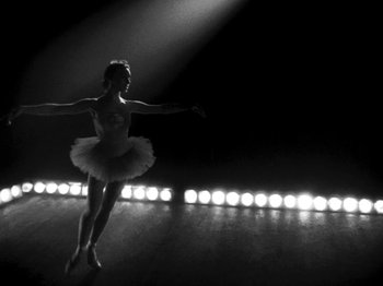 Movie still from “Killer's Kiss” (1955), directed by Stanley Kubrick – A woman in a white tutu is dancing on a stage; Wide shot, Low angle