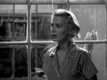 Movie still from “Killer's Kiss” (1955), directed by Stanley Kubrick – A black - and - white photo of a woman in front of a window; Close Up shot, Low angle