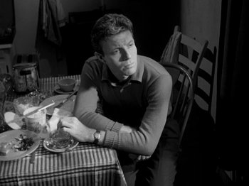 Movie still from “Killer's Kiss” (1955), directed by Stanley Kubrick – A black and white photo of a man sitting at a table; Medium shot, High angle