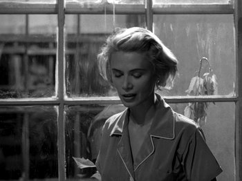 Movie still from “Killer's Kiss” (1955), directed by Stanley Kubrick – A black - and - white photo of a woman in front of a window; Close Up shot, Over the shoulder angle