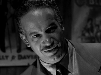 Movie still from “Killer's Kiss” (1955), directed by Stanley Kubrick – Black and white photograph of a man in a suit; Close Up shot, Low angle