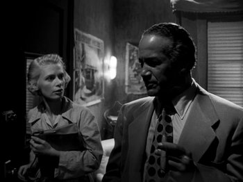 Movie still from “Killer's Kiss” (1955), directed by Stanley Kubrick – A man and a woman standing next to each other in a room; Medium shot, Low angle