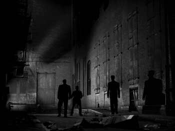 Movie still from “Killer's Kiss” (1955), directed by Stanley Kubrick – A group of men standing in a dark room; Extreme Wide shot, Low angle