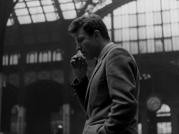 Movie still from “Killer's Kiss” (1955), directed by Stanley Kubrick – A black and white photo of a man smoking a cigarette; Medium shot, Low angle