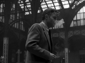 Movie still from “Killer's Kiss” (1955), directed by Stanley Kubrick – A black and white photo of a man smoking a cigarette; Medium shot, Low angle