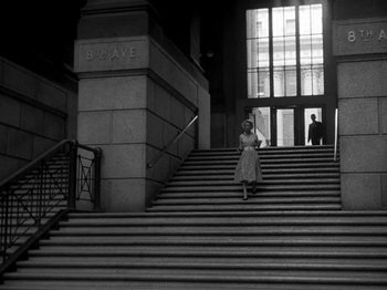 Movie still from “Killer's Kiss” (1955), directed by Stanley Kubrick – A black and white photo of a woman walking down a set of stairs; Extreme Wide shot, Low angle