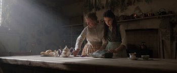 Movie still from “Enola Holmes” (2020), directed by Harry Bradbeer – Two women are standing at a table with a tea pot; Medium shot, Low angle