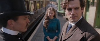 Movie still from “Enola Holmes” (2020), directed by Harry Bradbeer – A man and a woman standing next to each other on a train platform; Close Up shot, Over the shoulder angle