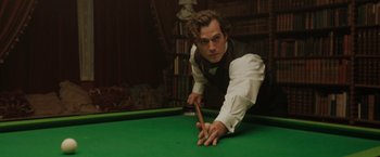 Movie still from “Enola Holmes” (2020), directed by Harry Bradbeer – A man in white shirt and vest playing a game of pool; Medium shot, Over the shoulder angle
