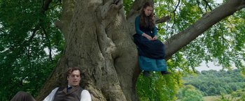 Movie still from “Enola Holmes” (2020), directed by Harry Bradbeer – A man and a woman sitting on a tree; Medium shot, Low angle