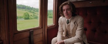 Movie still from “Enola Holmes” (2020), directed by Harry Bradbeer – A man in a suit and tie sitting on a train; Medium shot, Over the shoulder angle