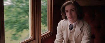 Movie still from “Enola Holmes” (2020), directed by Harry Bradbeer – A man in a suit and tie sitting in front of a window; Close Up shot, High angle