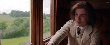 Movie still from “Enola Holmes” (2020), directed by Harry Bradbeer – A woman sitting in front of a window on a train; Close Up shot, Over the shoulder angle