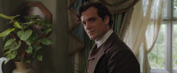 Movie still from “Enola Holmes” (2020), directed by Harry Bradbeer – A man wearing a suit and tie standing in front of a window; Close Up shot, Over the shoulder angle