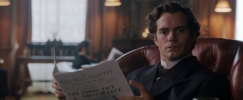 Movie still from “Enola Holmes” (2020), directed by Harry Bradbeer – A man sitting in a chair reading a newspaper; Close Up shot, Over the shoulder angle