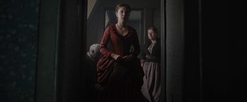 Movie still from “Enola Holmes” (2020), directed by Harry Bradbeer – A woman in a red dress holding a white teddy bear; Medium shot, Low angle