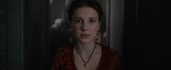 Movie still from “Enola Holmes” (2020), directed by Harry Bradbeer – A young woman wearing a necklace and earrings; Close Up shot, Low angle