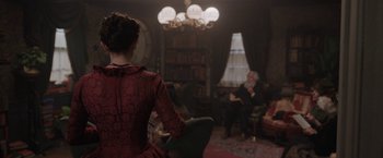 Movie still from “Enola Holmes” (2020), directed by Harry Bradbeer – A woman in a red dress in front of a man in a black suit; Medium shot, Over the shoulder angle