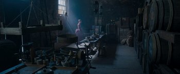 Movie still from “Enola Holmes” (2020), directed by Harry Bradbeer – A person standing in a room with a table of food; Wide shot, High angle