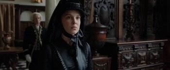 Movie still from “Enola Holmes” (2020), directed by Harry Bradbeer – A woman wearing a black dress and a black hat; Close Up shot, Over the shoulder angle