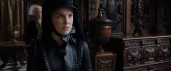 Movie still from “Enola Holmes” (2020), directed by Harry Bradbeer – A woman in a black dress and a black hat; Close Up shot, Over the shoulder angle